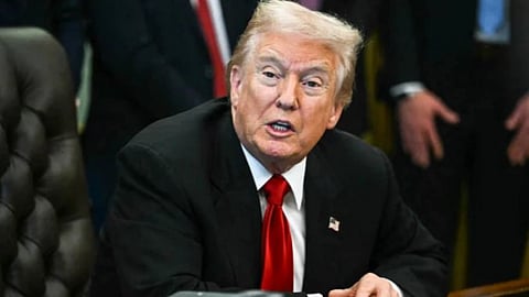 President Donald Trump speaking  during a meeting. He is sitting and his ministers are standing behind.