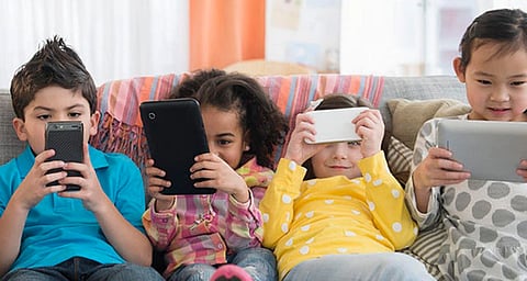 In the image childrens are shown using their mobile phones 