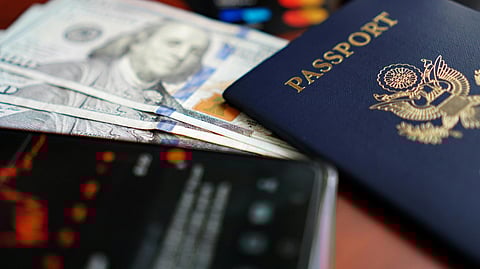Close-up of a blue cooured Passport, Dollars, and Smartphone placed at a table.