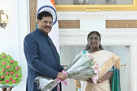CJI Gavai standing next to President Murmu with a bouquet of flowers in hand, in front of a marble wall.