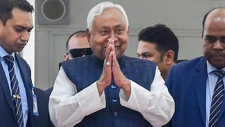 Chief Minister of Bihar Nitish Kumar standing by joining his hands in Namaste, surrounded by bodyguards. 