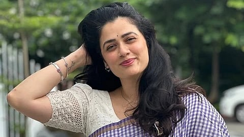 In the image Girija Oak is shown smiling and setting her hair 