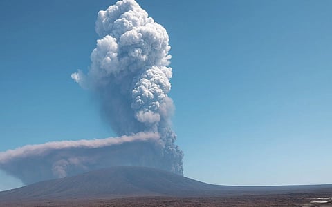 Image of Hayli Gubbi Volcano eruption with a large plume of ash and smoke rising against a clear blue sky, creating a dramatic and powerful scene.