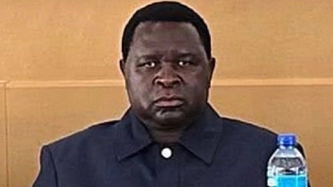 A close-up of Adolf Hitler uunona staring into the camera with a triaght face. A water bottle is visible in the bottom right of the frame.