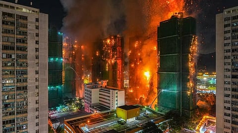 High-rise buildings engulfed in flames at night, with intense orange fire and thick smoke, creating a dramatic and chaotic scene in an urban area.