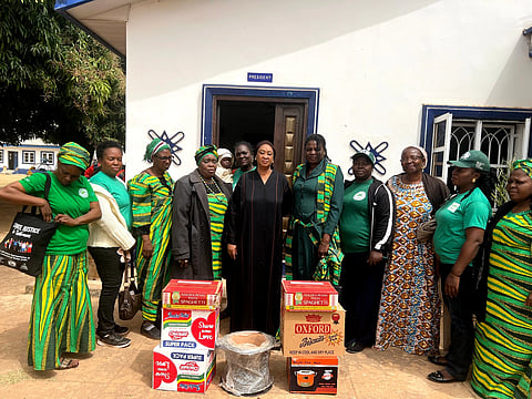 Women from WISE standing in front of a room marked 'President', with boxes of food in front of them.