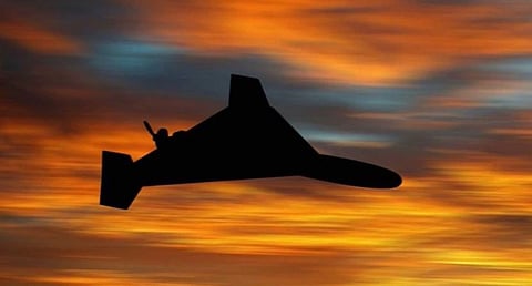 Silhouette of a drone flying against a dramatic sunset sky with vibrant orange, yellow, and blue hues, creating a serene yet mysterious atmosphere.