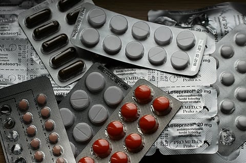 Blister packs of pills in various colors, including brown, gray, and red, are scattered over packaging labeled "Loseprazol 20 mg," creating a clinical tone.