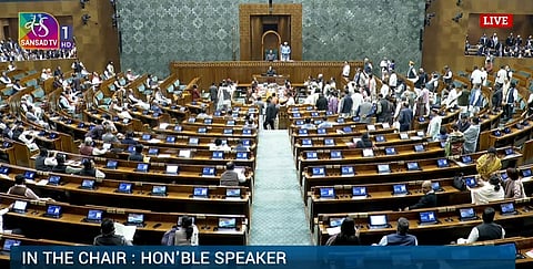 The first day of the Winter Parliament Session, 2025 is in session in the Lok Sabha, with the Honourable Speaker presiding in the chair. Some of the MPs of the Opposition (seated to the left of the speaker) are sitting while some are standing; whereas the Ruling Government Coalition MPs (seated to the right of the speaker) are sitting.