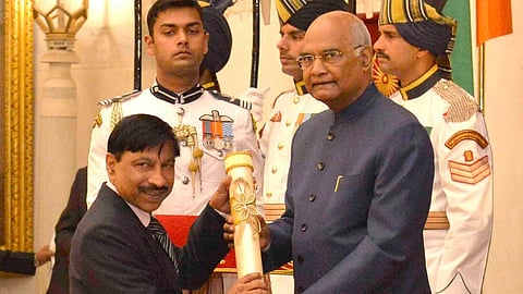 KK Muhammed receiving an award from Ram Nath Kovind, with ceremonial guards standing in the background.