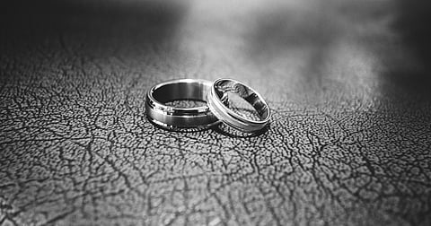 A black and white picture of two silver rings rest on a textured surface.