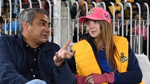 Pakistani Interior Minister Mohsin Naqvi and UK High Commissioner Jane Marriott sitting next to each other, talking. Naqvi is in a blue jacket, Marriott is in a yellow jacket and pink cap.