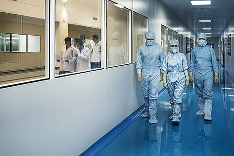 medical workers walking in hazmat suits inside the Biocon facility.