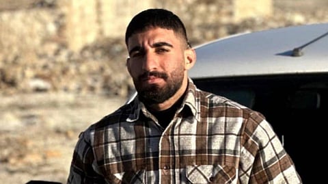 A screenshot of Omid Sarlak from his Instagram account showing him standing in front of his car in a checked shirt.