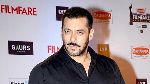 Salman Khan in a black shirt poses confidently on the red carpet at a Filmfare event. Background features event logos and a lively, formal atmosphere.