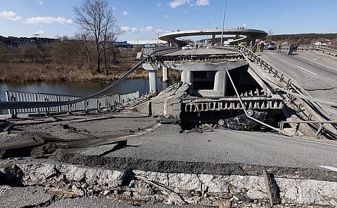 Image depicting a scene of Russia Ukraine war. In the image there is  Outskirts of Kyiv after Russian invasion of Ukraine. the image is of A collapsed bridge over a river with visible destruction, exposing metal supports and an overturned car beneath. 
