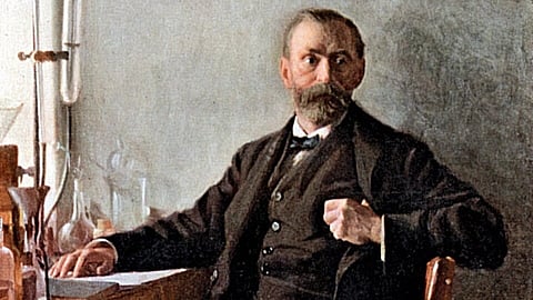 Alfred Nobel with a beard sits thoughtfully at a lab desk with glassware. He wears a dark suit, exuding an aura of intellect and contemplation.