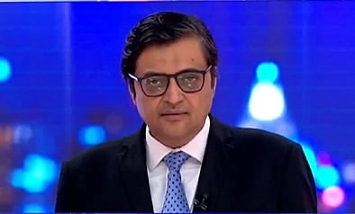 In the image Republic Bharat editor is chief Arnab Goswami is shown looking at camera with a serious face his background is blur with some blured lights and he is wearing White shirt and coat in a professional setting