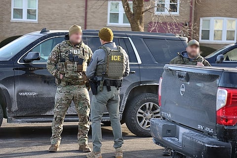 The image depicts US Immigration and Customs Enforcement Officers in their unifroms. 