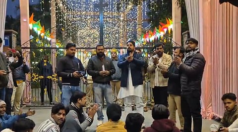 The image depicts several Bajrang Dal members outside a church in Bareilly reciting Hanuman Chalisa. People are sitting in a group, and some are standing, the church is decorated with lights and stars ahead of Christmas celebrations.