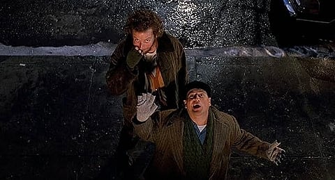 A screenshot from Home Alone 2: Lost in New York showing the wet bandits standing on the street. One, Marv, is biting his nails, the other, Harry, is looking up and shouting.