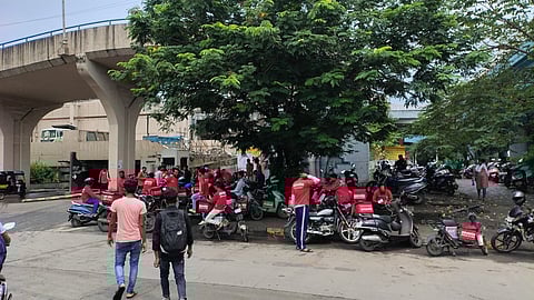Zomato workers stand under a tree and flyover while on strike in Mumbai, September 2024.
