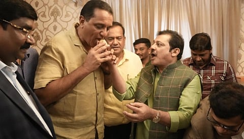 In the image Sarfaraz Khan is shown eating sweats from the hands of another man wehind them are other men standing the image looks like celebration