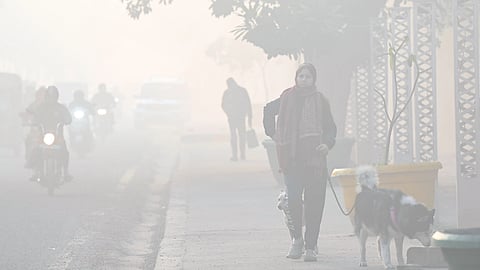 Noida: Commuters walk along a road amid smog on a chilly morning as air pollution worsens, with the Air Quality Index (AQI) recorded at 432 in the severe category in Noida on Tuesday, December 23, 2025.