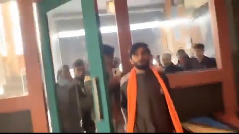 A Bajrang Dal member walking through a door with a mob behind him.