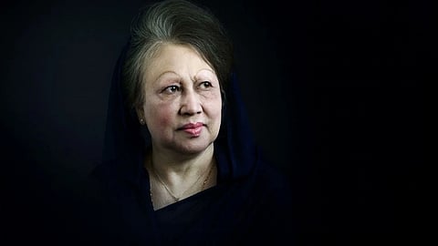Former PM of Bangladesh Begum Khaleda Zia with a gentle expression, wearing a dark headscarf, is gazing to the side against a dark background.