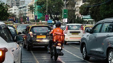 A Swiggy rider on a bike in the middle of traffic.