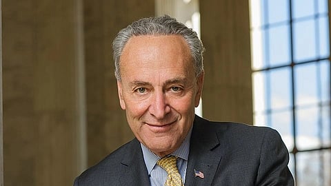 In the image US Senate Minority Leader Chuck Schumer  is shown standing posing to the camera