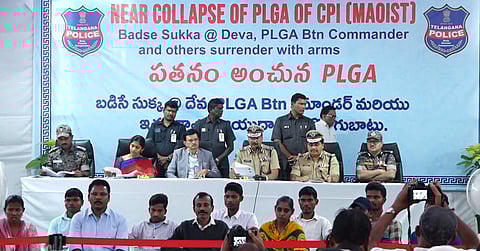 Telangana DGP B Shivadhar Reddy addressed a press conference where Barsa Deva along with other Maoist commanders surrendered today. He is surrounded by other leaders of the Police and administration, while the Maoists who surrendered are sitting in front row. The poster behind says: "Near Collapse of PLGA of CPI (Maoist), Badse Sukka @ Deva, PLGA Btn Commander and others surrender with arms". Other text is in Telugu.