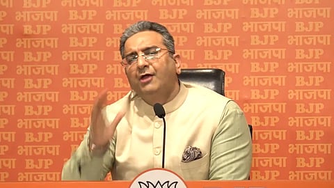 BJP National Spokesperson Gaurav Bhatia sitting in front of a mic and an orange background, addressing the press at the party's headquarters.