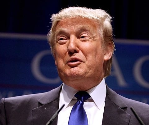 Image of Trump speaking in his black suit and blue tie. he is speaking at CPAC 2011 in Washington, D.C.