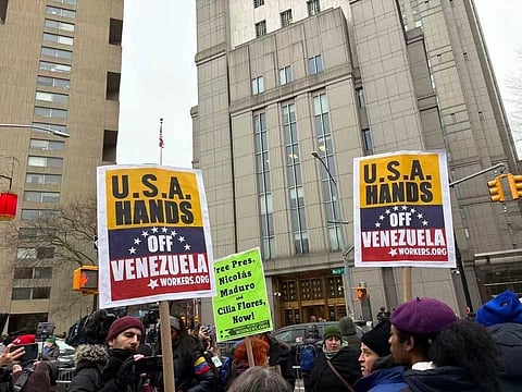 The image shows a protests against US for illegally attacking Venezuela. People hold posters that read "USA Hands Off Venezuela", and "Free Nicolas Maduro". 