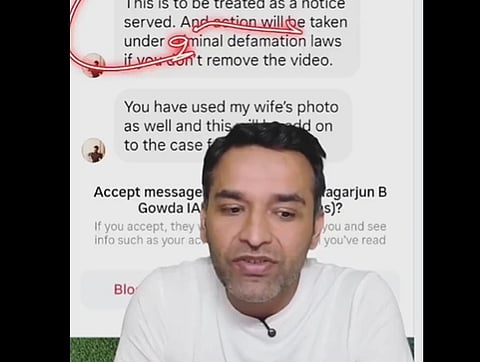 Screenshot from Amit Kilhor social media post. He is wearing  a white shirt is speaking in front of a blurred screenshot showing a message about defamation laws. The tone seems serious and concerned.