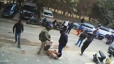 Screenshot of CCTV footage showing a man being beaten in the middle of the road while a crowd watches.