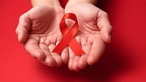 The image shows a pair of hands holding the HIV-AIDS prevention symbol, the background is red colour.