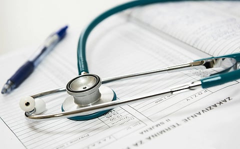 A stethoscope rests on a medical chart filled with data, alongside a blue pen. The scene conveys a sense of healthcare, precision, and professionalism.