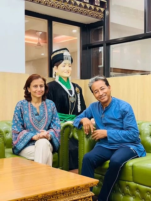 Sonam Wangchuk and Gitanjali Angmo sitting together in front of a statue.