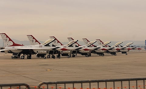 Eight U.S. Air Force Thunderbirds jets lined up on an airfield, overcast sky. The planes are red, white, and blue, showcasing precision and readiness. Lockheed Martin F-16C Fighting Falcons of the United States Air Force Thunderbirds parked during Aviation Nation 2017.