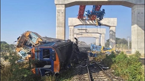 A train derailed on tracks beneath an under-construction bridge. Several cars are overturned, surrounded by debris, conveying a scene of devastation in Thailand.