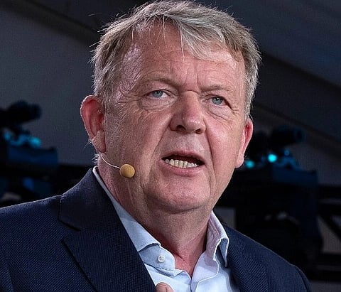 Image of Denmark’s Foreign Minister Lars Løkke Rasmussen  with a mic on his right cheek. he is giving a speech with his right hand placed on his chest. 