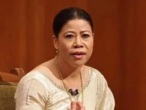 Image of Olympic boxer MaryKom in a white embroidered outfit. She is speaking, seated against a wooden backdrop at Rajat Sharma's Aap ki Adalat. Her expression is focused and engaged, suggesting a serious discussion.