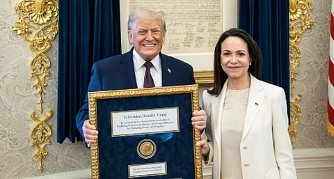 Image of President Donald Trump (left) holding the nobel peace prize medal in a frame which was presented to him by Venezuelan opposition leader Maria Corina Machado (right) to him. 