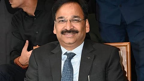 Suspended IAS Vinay Chaubey in a suit, smiling at the camera.