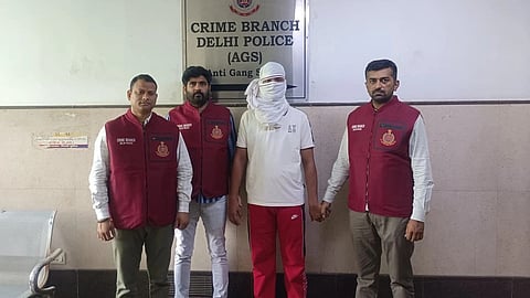 Officers from Delhi Police's Crime Branch stand with the accused in custody in front of a board that reads 'Crime Branch Delhi Police (AGS)'.
