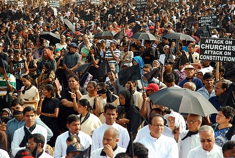 An image of the Christian protests against the Somasekhara Commission report in Mangalore. A large crowd can be seen with some umbrellas and placards held up.
