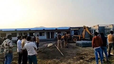 Screenshot from a video showing authorities demolishing part of SK Public school. A bulldozer can be seen alongside police personnel and residents of Dhaba.